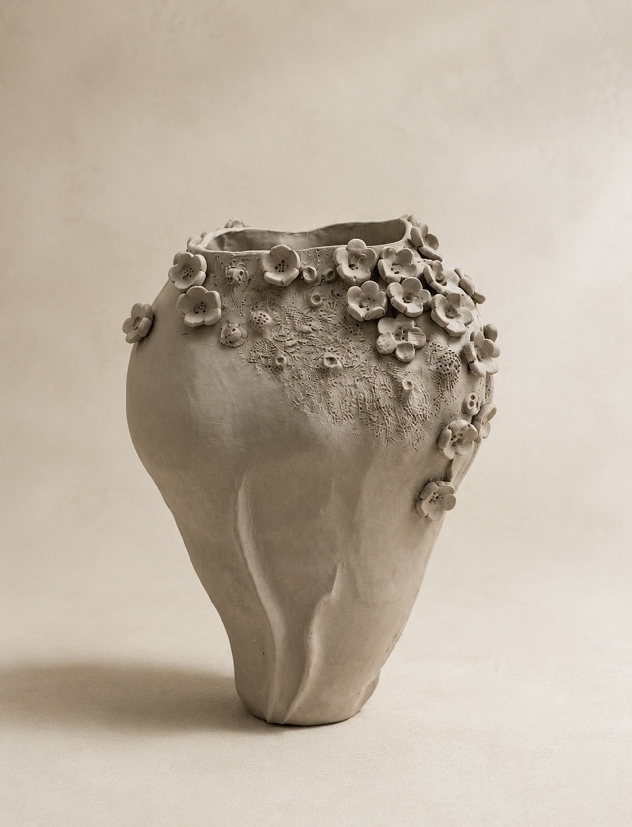 Tall handbuilt ceramic vase decorated with sculpted flowers