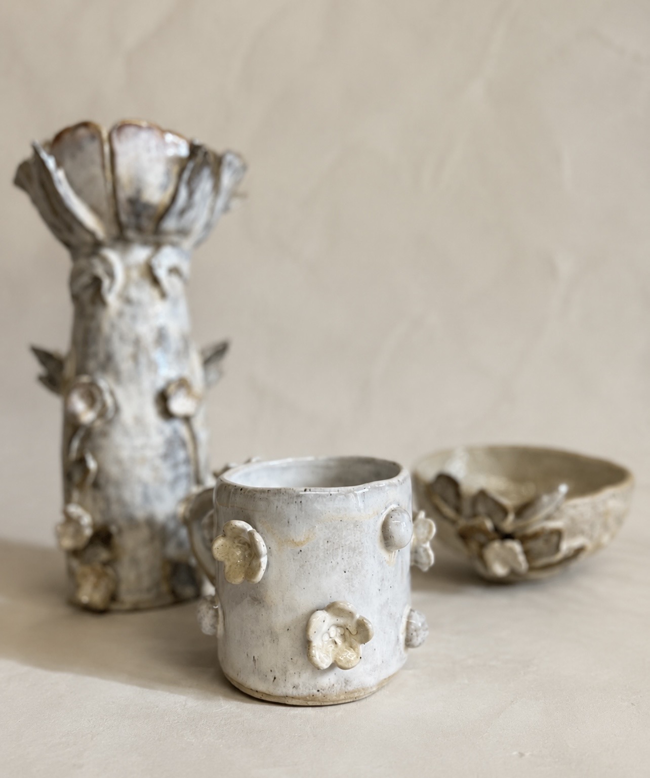 Floral ceramic mug with matching sculptural vessels and bowl