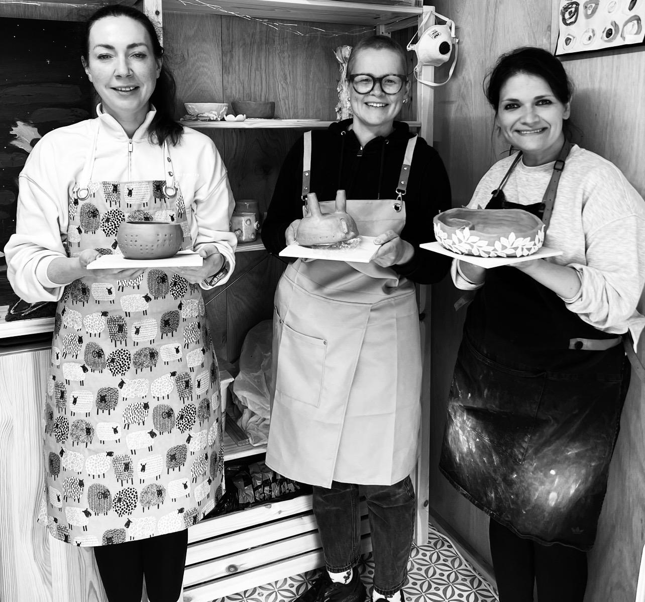 Three workshop guests smiling with their handmade ceramic pieces